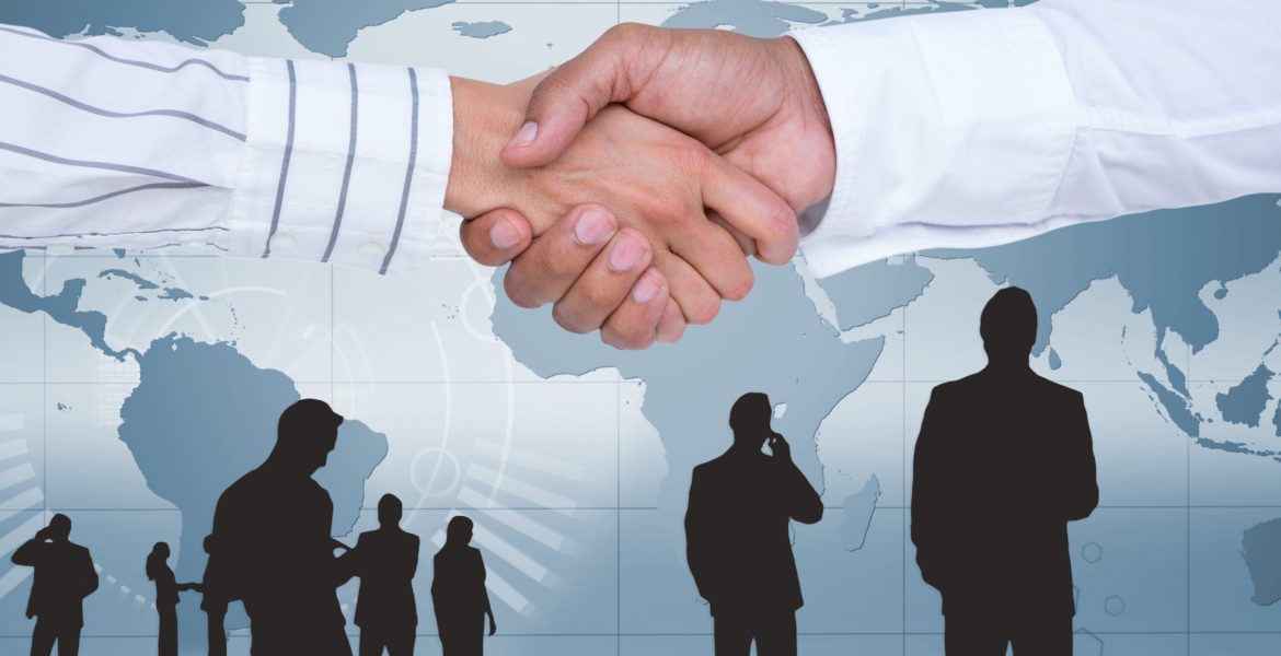Businesspeople shaking hands against map background